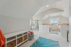 Carpeted bedroom featuring a textured ceiling and vaulted ceiling