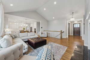 Living room with recessed lighting, baseboards, light wood-style flooring, and vaulted ceiling