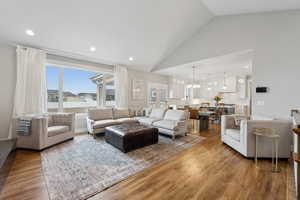Living area with an inviting chandelier, recessed lighting, wood finished floors, and high vaulted ceiling