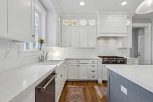 Kitchen with glass insert cabinets, dark wood-style floors, white cabinets, stainless steel appliances, and a sink