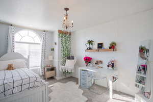 Bedroom with light colored carpet, baseboards, and a chandelier