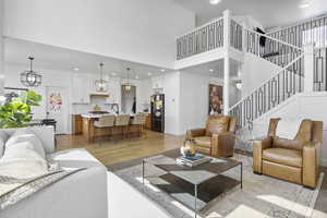 Living area featuring light wood-type flooring, recessed lighting, a high ceiling, baseboards, and stairs
