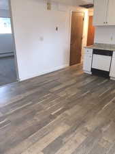 Kitchen featuring a baseboard heating unit, dark wood finished floors, white cabinets, white dishwasher, and baseboards