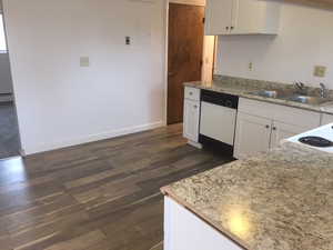 Kitchen featuring a sink, dark wood finished floors, white cabinets, baseboards, and dishwasher