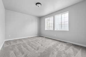 Carpeted empty room with visible vents and baseboards