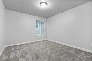 Carpeted empty room with baseboards and a textured ceiling