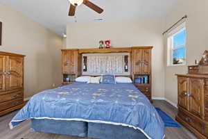 Bedroom with wood finished floors, visible vents, baseboards, ceiling fan, and vaulted ceiling