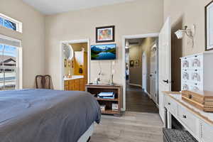 Bedroom featuring light wood finished floors, visible vents, and ensuite bathroom