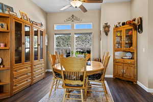 Dining space featuring dark wood-type flooring, baseboards, and ceiling fan