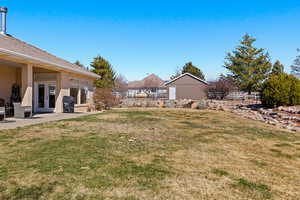 View of yard featuring a patio, fence, an outbuilding, and french doors