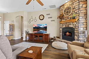 Living area featuring a ceiling fan, dark wood-style floors, arched walkways, and visible vents