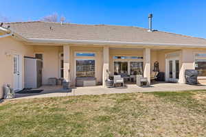 Back of property featuring a tile roof, a lawn, french doors, stucco siding, and a patio