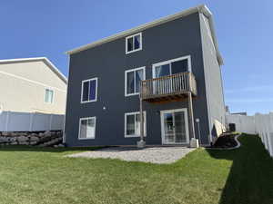 Back of house featuring a fenced backyard, central AC unit, a lawn, a balcony, and stucco siding