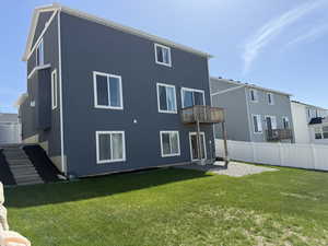 Rear view of property featuring stairway, stucco siding, a lawn, and fence