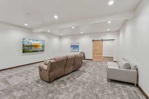 Living area with carpet floors, recessed lighting, and a barn door