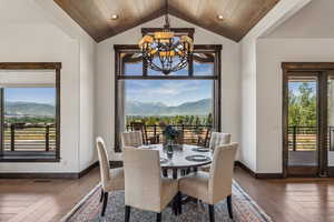 Dining area featuring a chandelier, a mountain view, hardwood / wood-style flooring, lofted ceiling, and wood ceiling