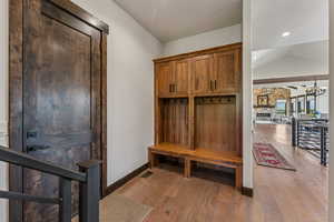 Mudroom featuring vaulted ceiling, light wood-style floors, and a chandelier
