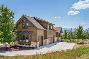 View of front of home featuring stone siding, concrete driveway, a mountain view, and an attached garage