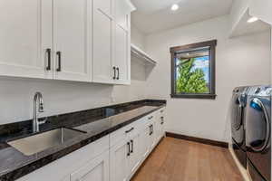 Washroom featuring washer and dryer, cabinet space, light wood-style floors, and recessed lighting