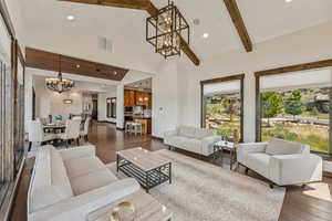 Living room featuring a chandelier, dark wood finished floors, recessed lighting, high vaulted ceiling, and beam ceiling