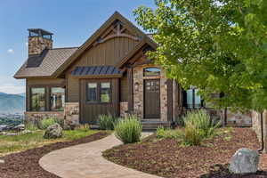 Craftsman-style home with stone siding, a standing seam roof, board and batten siding, and a metal roof
