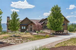View of front of home with stone siding and a chimney