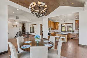 Dining area featuring a chandelier, recessed lighting, stairs, dark wood-style flooring, and high vaulted ceiling