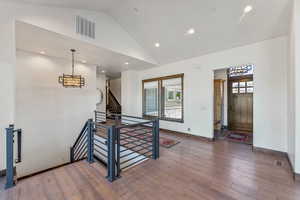Entrance foyer with vaulted ceiling, healthy amount of natural light, wood-type flooring, a chandelier, and recessed lighting