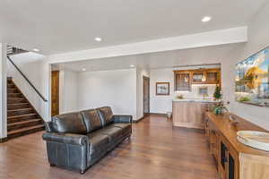 Living room featuring dark wood finished floors, stairs, recessed lighting, and bar area