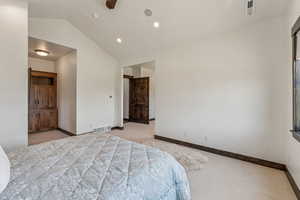 Bedroom with light colored carpet and vaulted ceiling