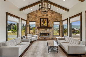 Living area featuring a large fireplace, wood finished floors, beam ceiling, recessed lighting, and a chandelier
