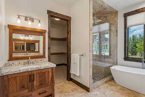 Full bath with a shower stall, a freestanding bath, and vanity