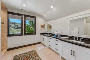Bathroom featuring double vanity, lofted ceiling, and recessed lighting