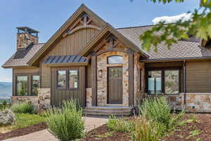 View of front of house with stone siding, board and batten siding, and a shingled roof