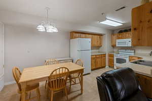 Kitchen featuring visible vents, light countertops, an inviting chandelier, white appliances, and a sink