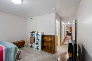 Bedroom with light colored carpet, visible vents, and a textured ceiling
