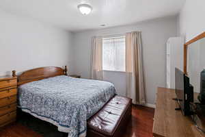 Bedroom with baseboards, dark wood-style floors, visible vents, and a textured ceiling