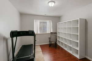 Workout area with visible vents, baseboards, a textured ceiling, and wood finished floors