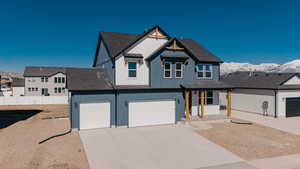 View of front of house with an attached garage, a shingled roof, concrete driveway, board and batten siding, and a mountain view