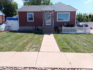 Bungalow featuring brick siding, fence private yard, a front lawn, and a gate