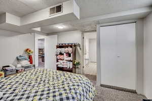 Carpeted bedroom with a textured ceiling and a closet
