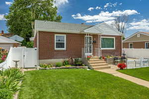Bungalow-style house with a gate, brick siding, and a fenced backyard