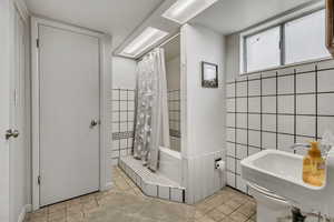 Full bathroom featuring tile walls, a tile shower, and tile patterned flooring