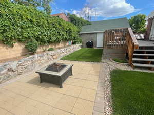 View of yard featuring an outdoor fire pit, a wooden deck, and a patio