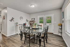 Dining room featuring wood finished floors, a textured ceiling, and french doors