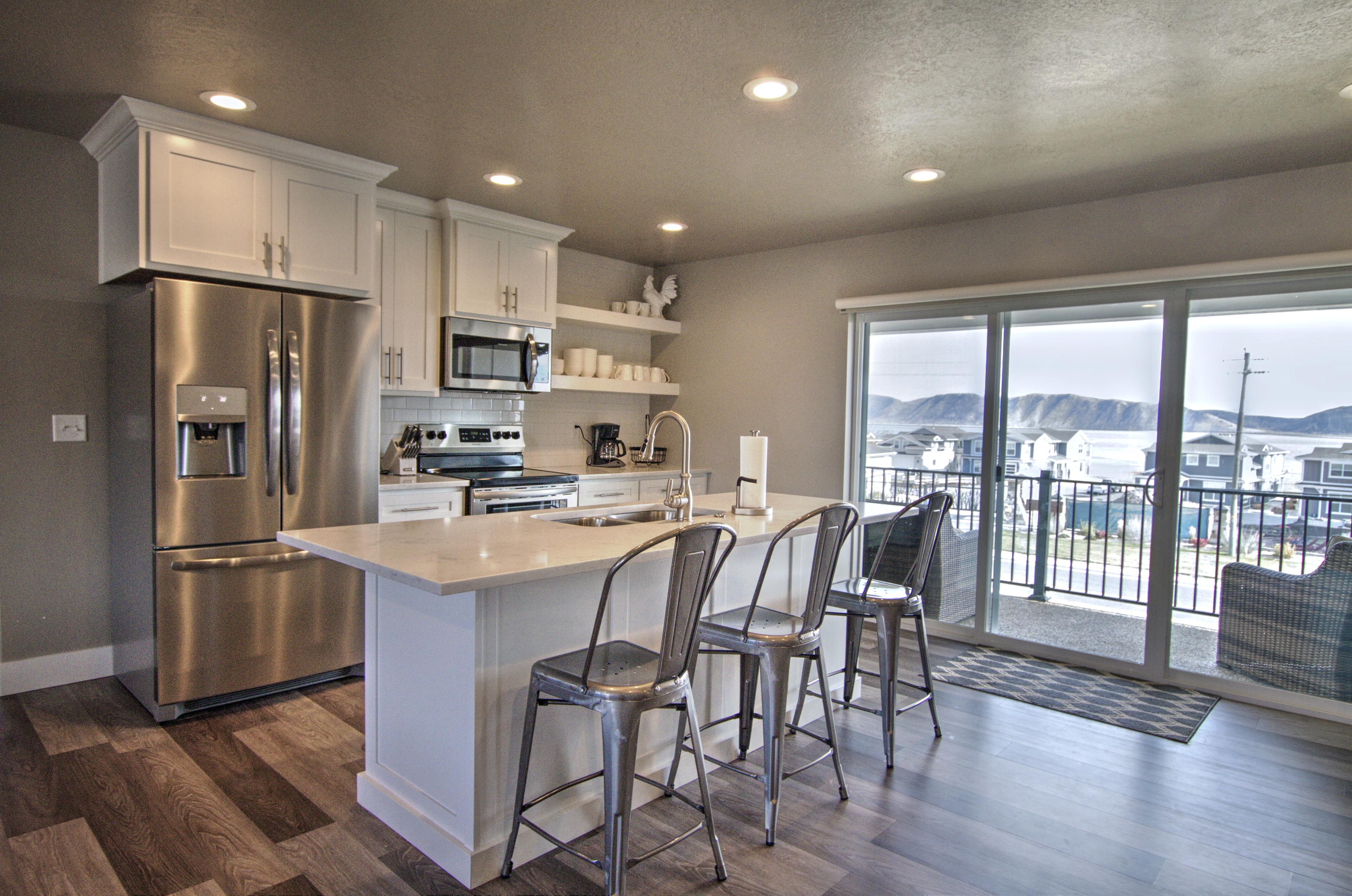 Kitchen featuring a center island with sink, dark wood finished floors, light countertops, appliances with stainless steel finishes, and backsplash