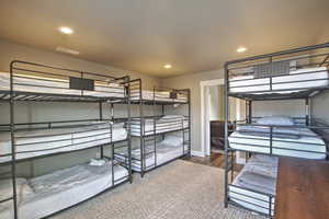 Bedroom with wood finished floors, recessed lighting, visible vents, and baseboards
