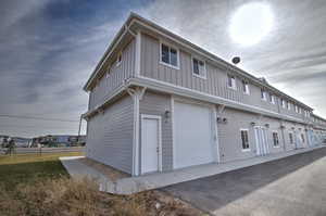Exterior space with a lawn, board and batten siding, driveway, and a garage