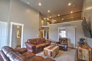 Living area featuring recessed lighting, visible vents, a towering ceiling, and baseboards