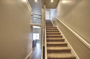 Stairs featuring a high ceiling, baseboards, and wood finished floors